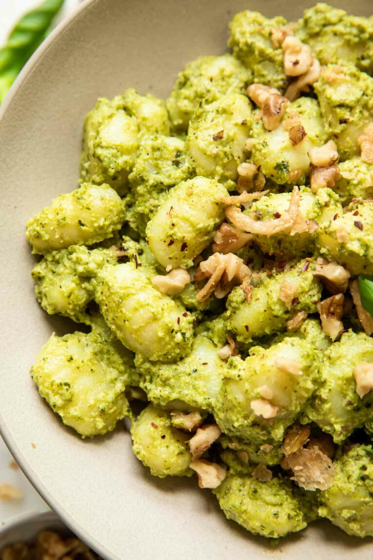 Close up image of creamy pesto gnocchi in a bowl.