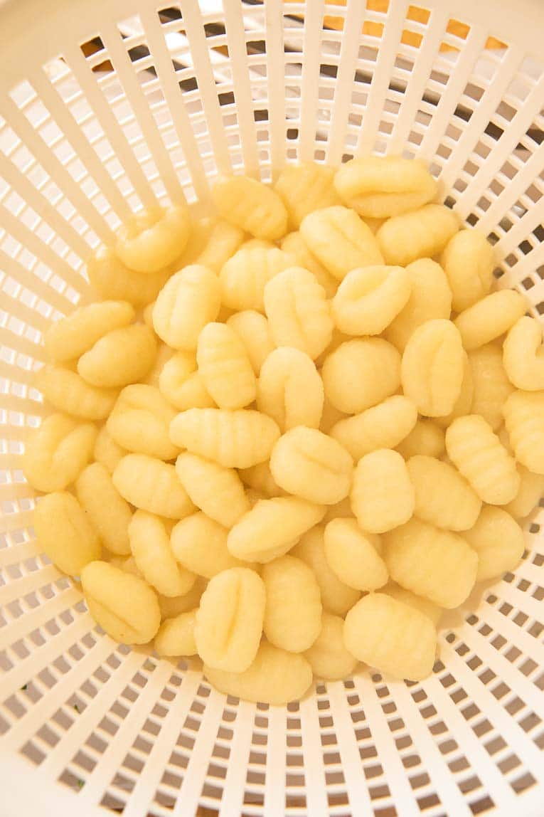 Cooked gnocchi in a strainer.