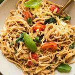 Creamy Brie Pasta Recipe in a white bowl with basil, spinach, and tomatoes.