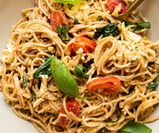 Creamy Brie Pasta Recipe in a white bowl with basil, spinach, and tomatoes.