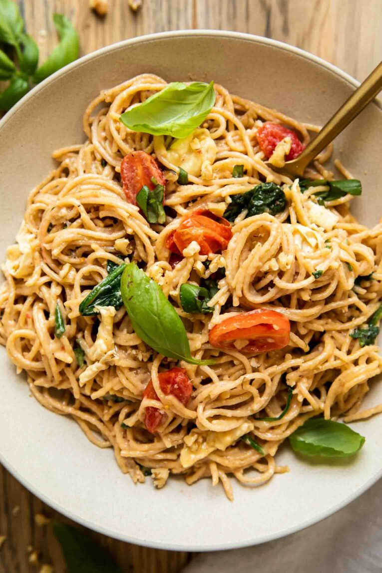 Creamy Brie Pasta Recipe in a white bowl with basil, spinach, and tomatoes.