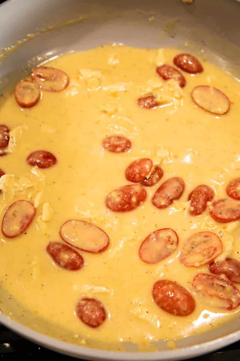Brie cheese sauce with tomatoes in a pan.