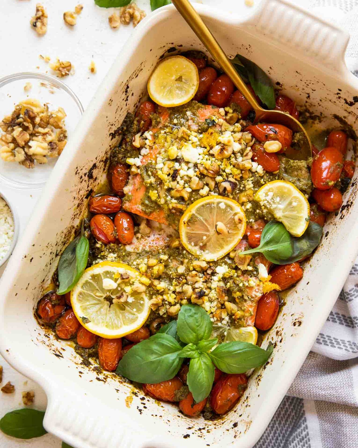 Baked pesto salmon in a casserole dish with tomatoes and basil.