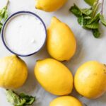 Lemons, sugar, and mint on a marble board.
