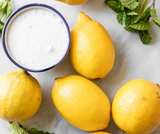 Lemons, sugar, and mint on a marble board.