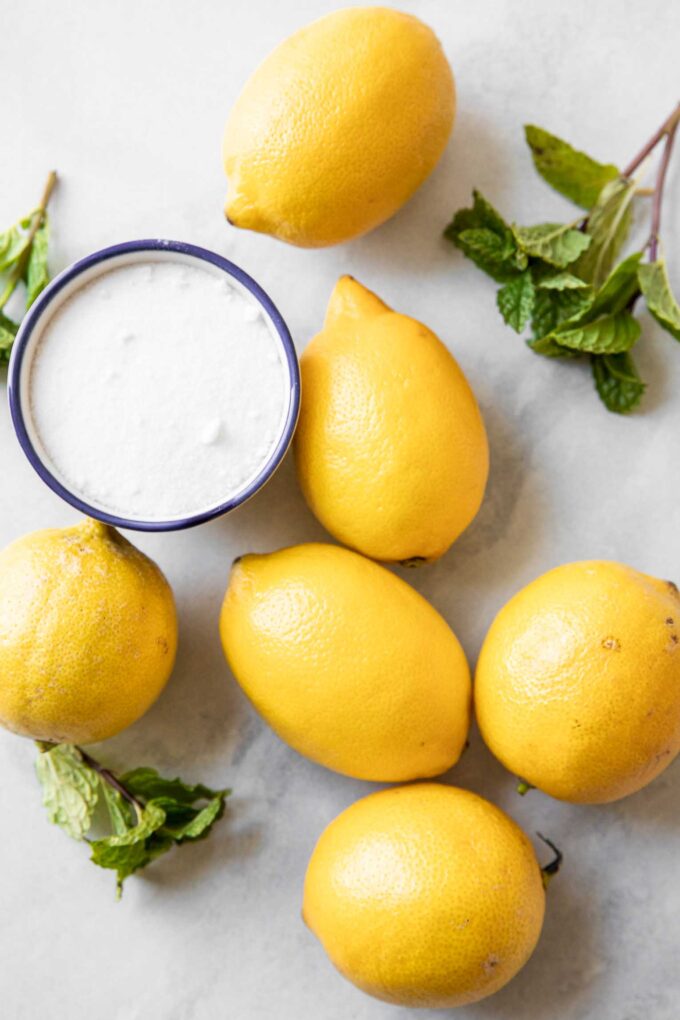 Lemons, sugar, and mint on a marble board.