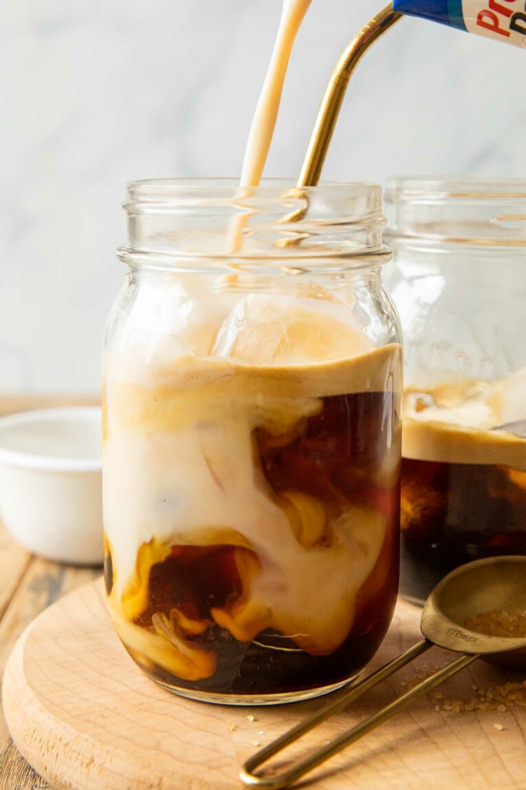 Protein shake being poured into iced coffee.