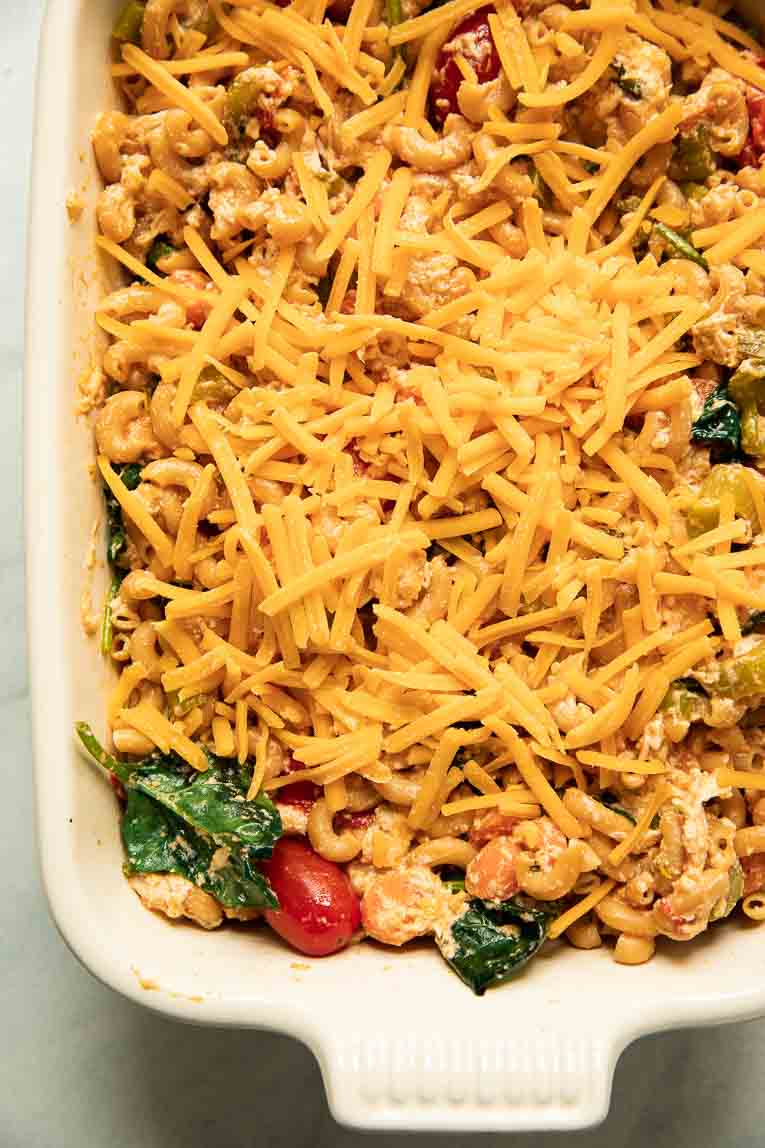 Buffalo chicken pasta topped with cheddar cheese in a casserole dish.