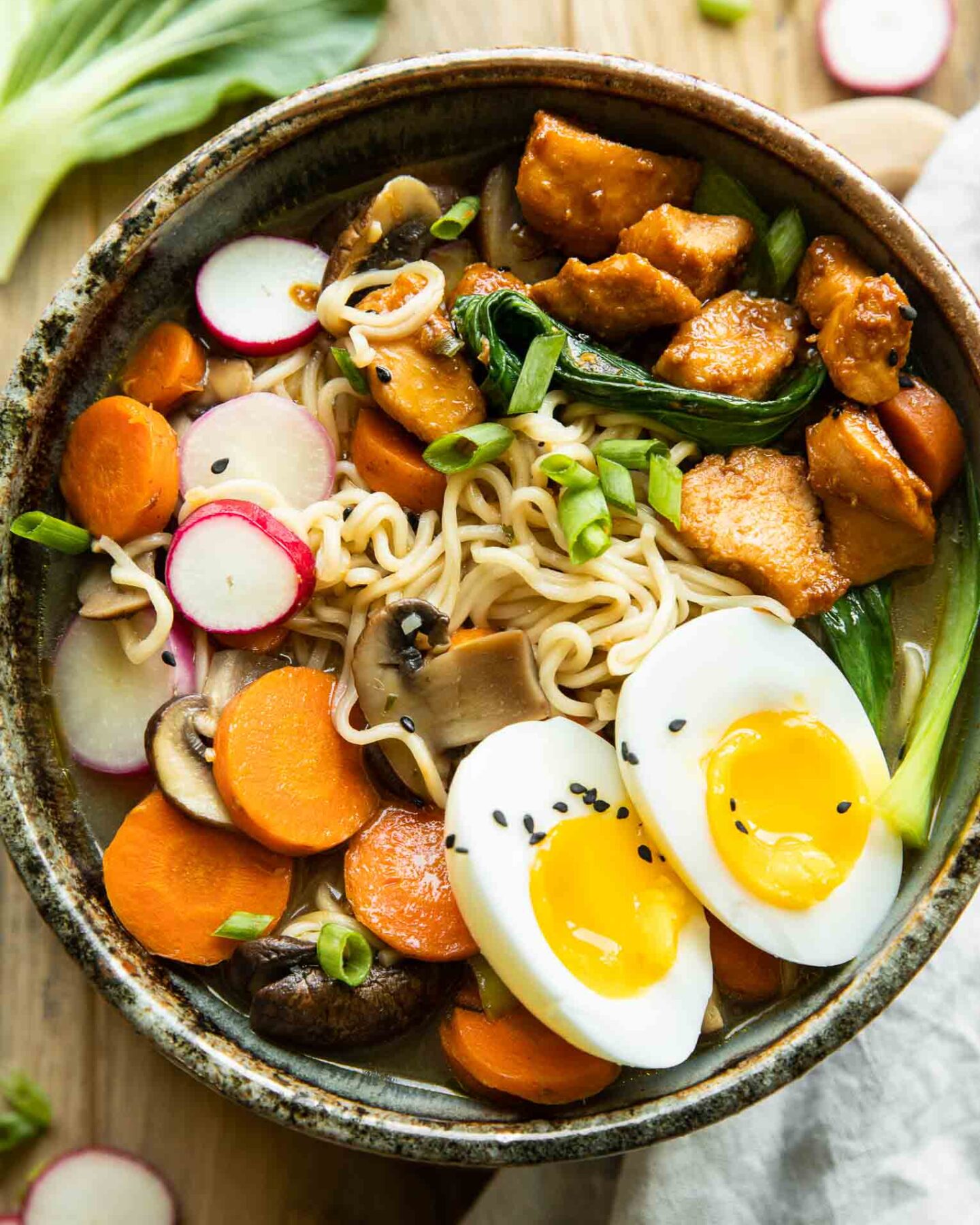 Spicy chicken ramen in a large bowl on a wood background.