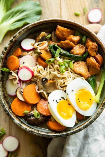 Spicy chicken ramen in a large bowl on a wood background.