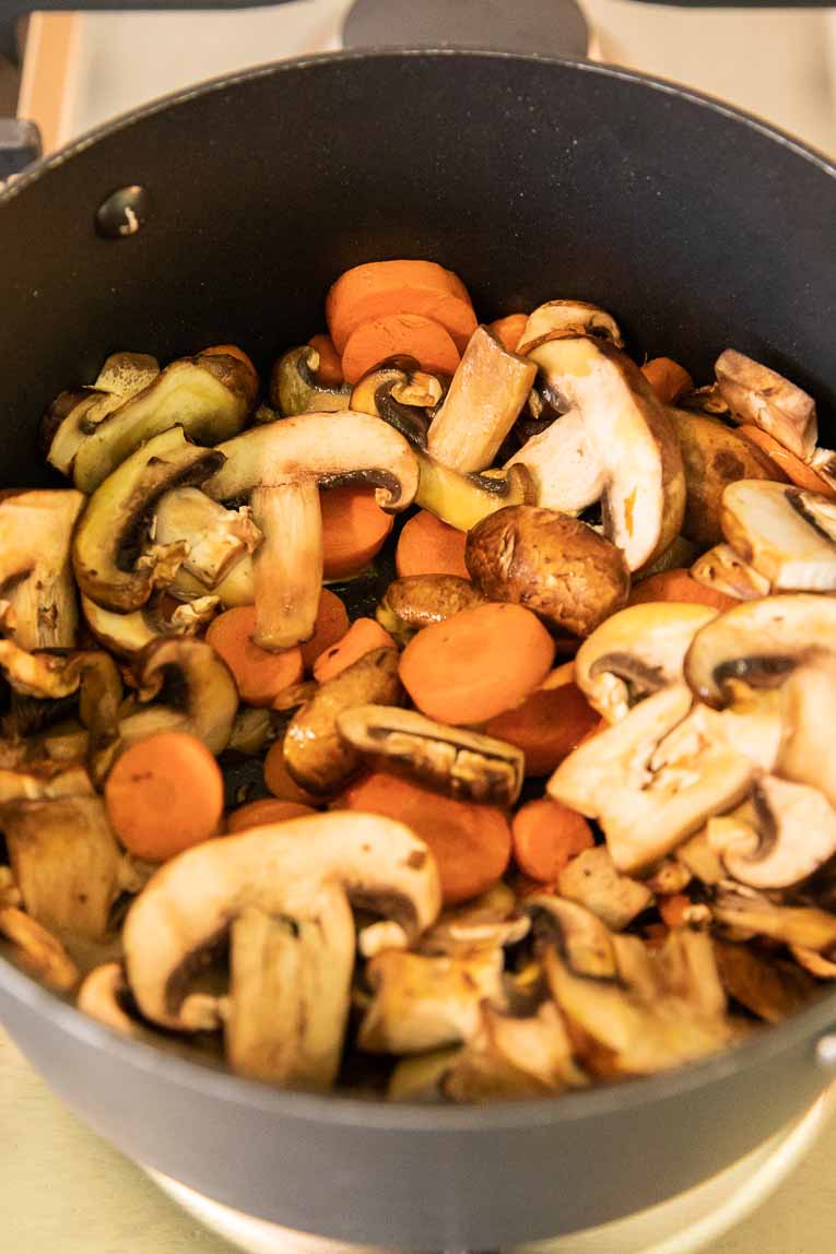 Mushrooms and carrots being sautéed.