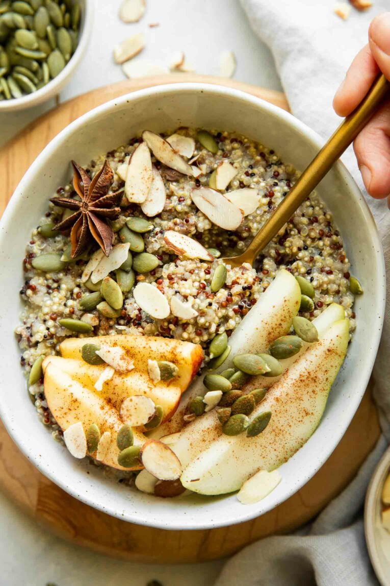 Breakfast quinoa bowl with hand and spoon.