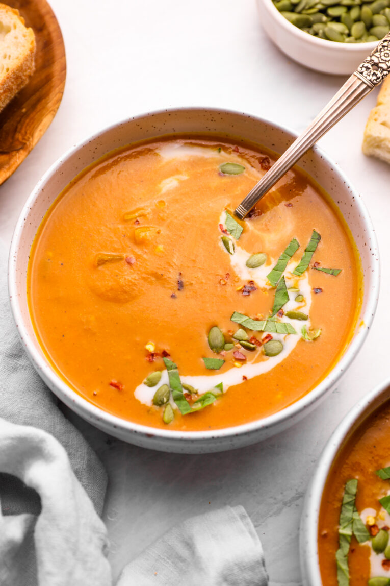 Pumpkin curry soup recipe with a spoon and toppings.