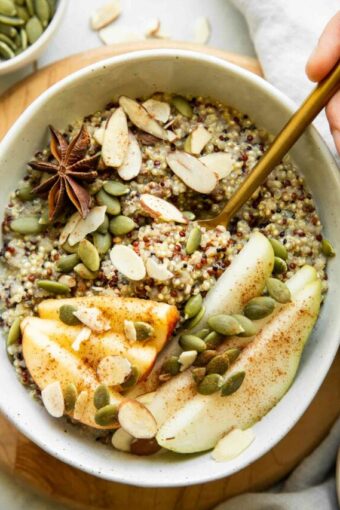 Breakfast quinoa bowl with hand and spoon.
