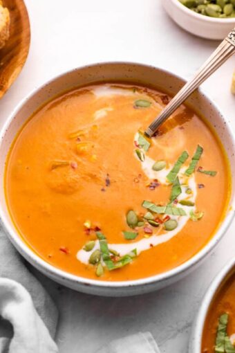 Pumpkin curry soup recipe with a spoon and toppings.