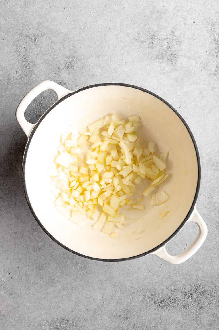 Onion being sautéed in a dutch oven.