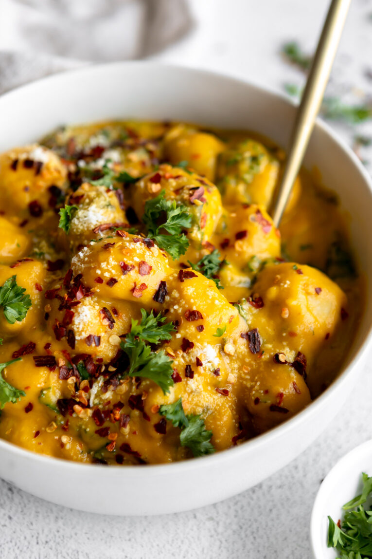 Angled photo of butternut squash gnocchi in a bowl with a fork.