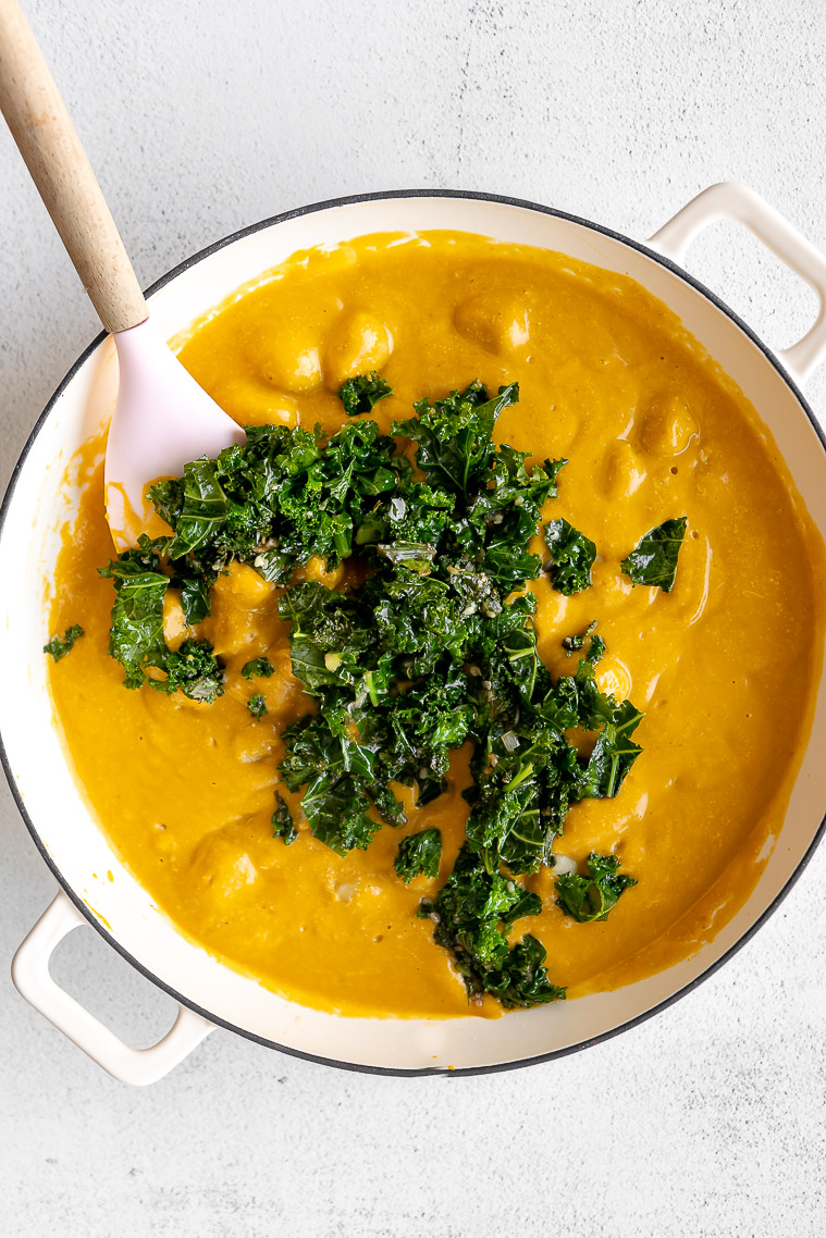 Butternut squash gnocchi with sauce and kale in a dutch oven.