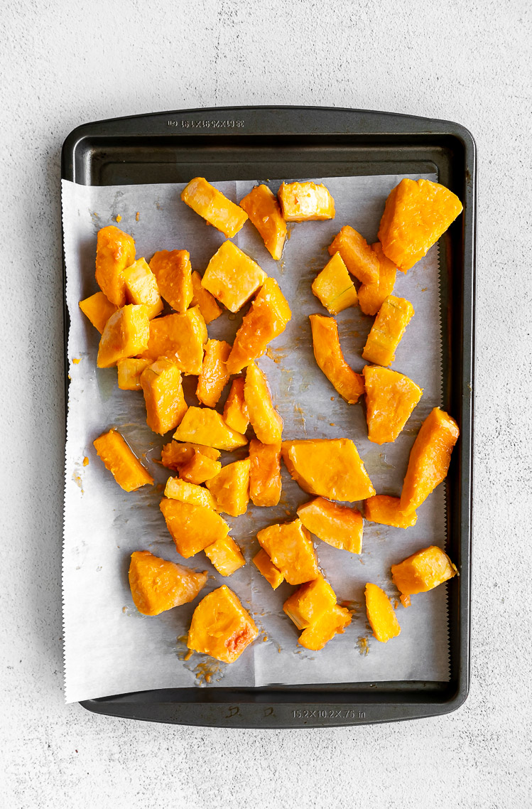 Butternut squash being roasted on a sheet pan.
