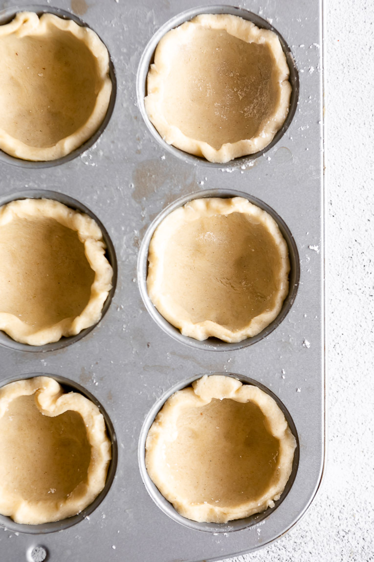 Pie dough pressed into muffin tin for mini pies.