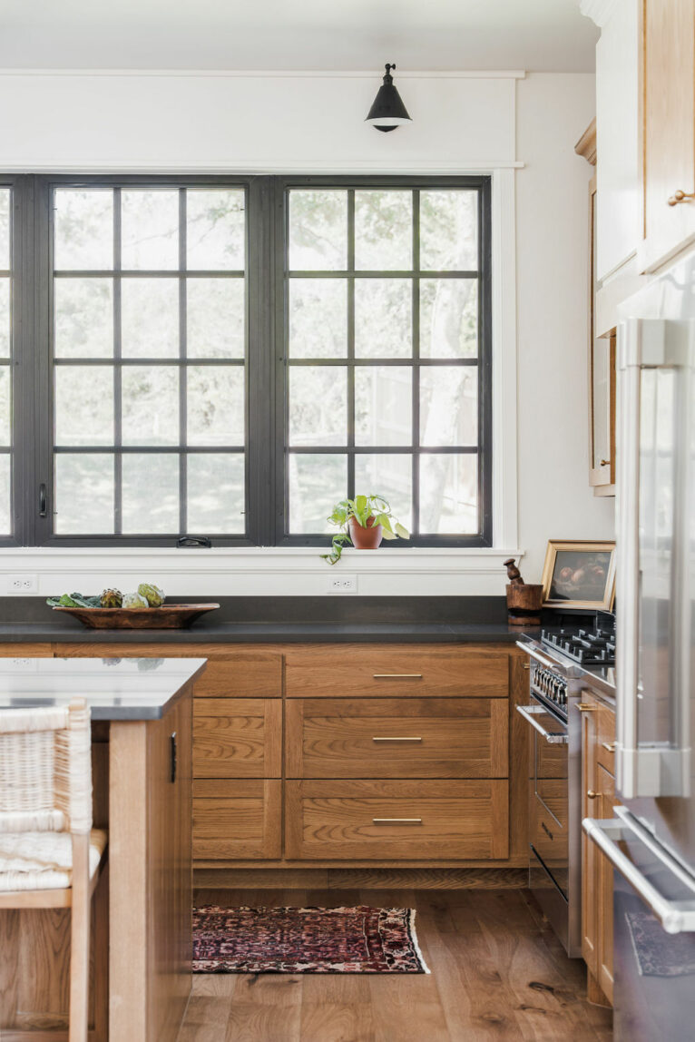 Black grid windows and black quartz countertops with wood stained drawers.