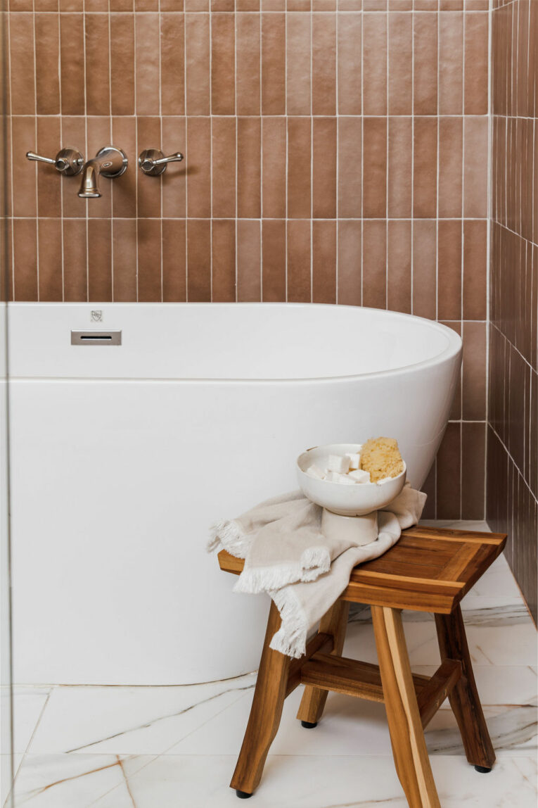 Close up of terra cotta tile with white bathtub and marble floor tile.