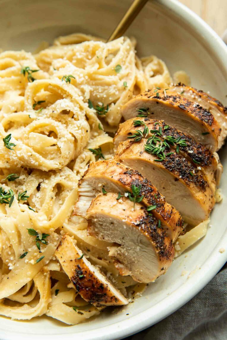 Close up of seasoned, seared chicken with healthy cauliflower alfredo.