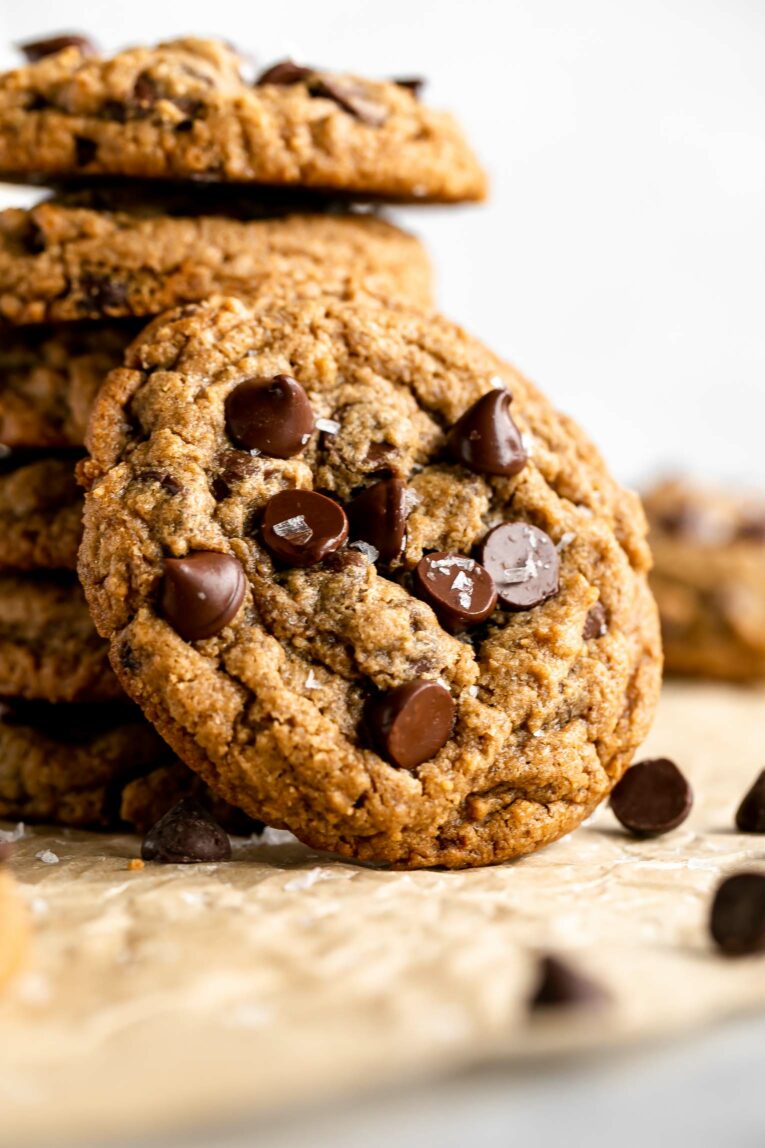 Close up of Oat Flour Chocolate Chip Cookie leaning on stack of other cookies.