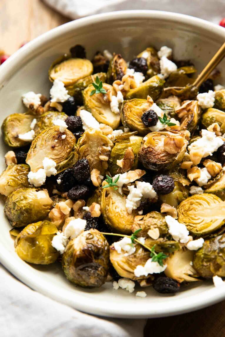 Angled photo of roasted brussels sprouts in a bowl with goat cheese and cranberries.