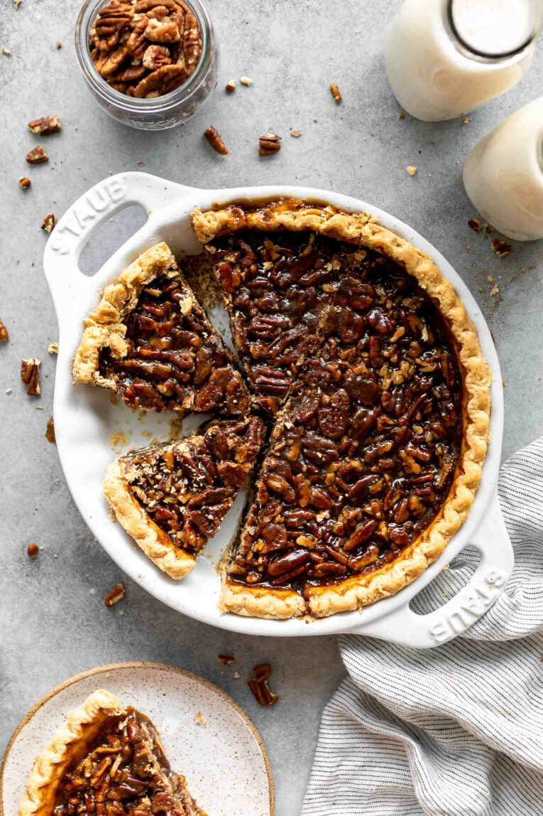Vegan pecan pie in a pie dish with slice taken out.