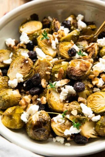 Angled photo of roasted brussels sprouts in a bowl with goat cheese and cranberries.