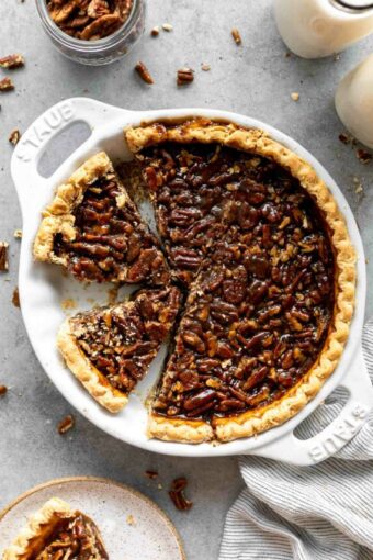 Vegan pecan pie in a pie dish with slice taken out.