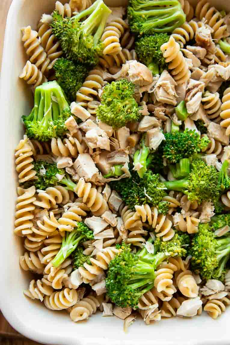 Cooked pasta, chicken, and roasted broccoli in a baking dish.