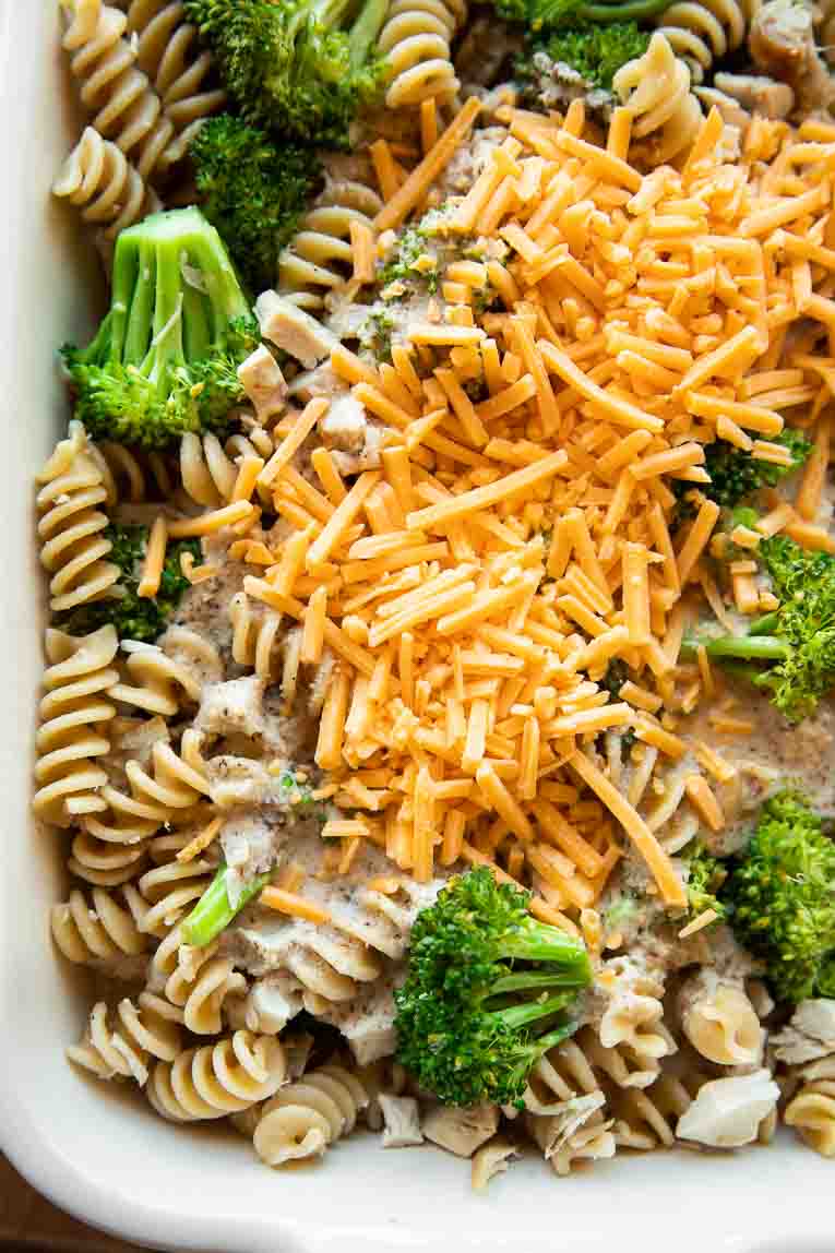 Cooked pasta, broccoli, and chicken with dairy free sauce and vegan cheese.
