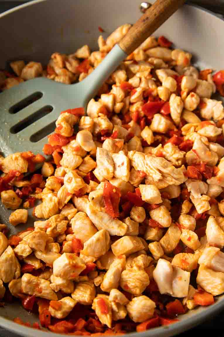 Chicken and bell peppers in a skillet.