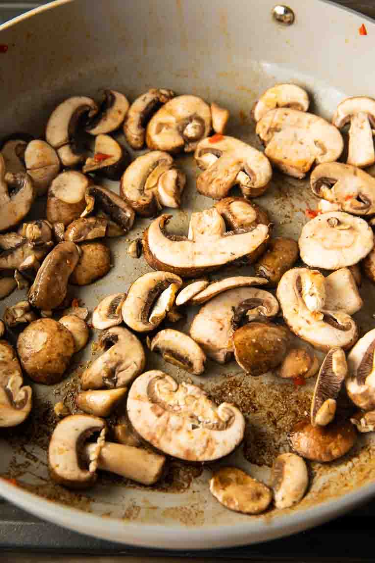 Mushrooms being sautéed in a pan.