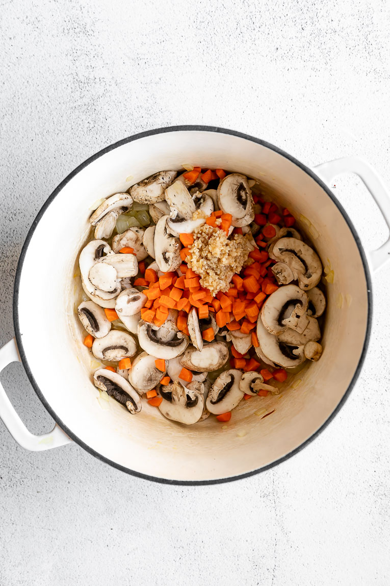 Vegetables being sautéed in a dutch oven.