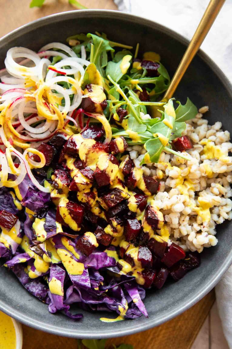 Close up of roasted beets bowls with turmeric tahini and vegetables/grains.