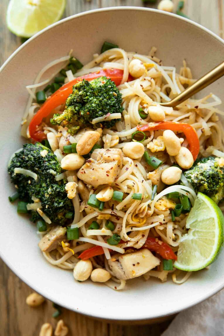 Chicken Pad Thai with peanuts and green onions in a bowl.