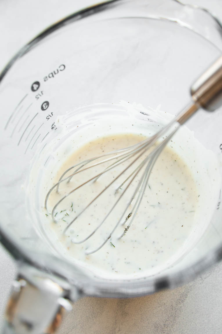 Greek yogurt dill sauce being whisked.