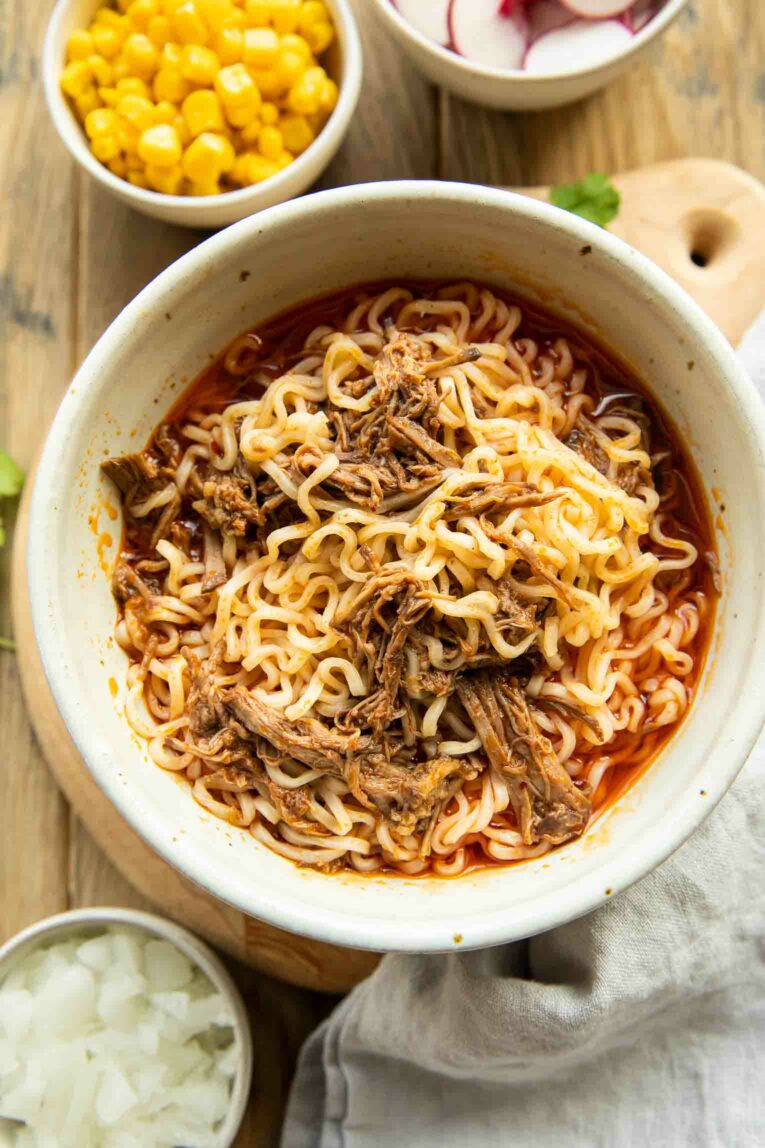 Birria Ramen in a bowl with toppings all around.