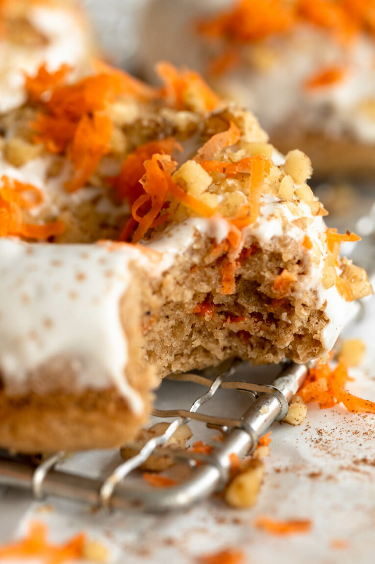 Bite taken out of Vegan Carrot Cake Donut on a cooling rack.