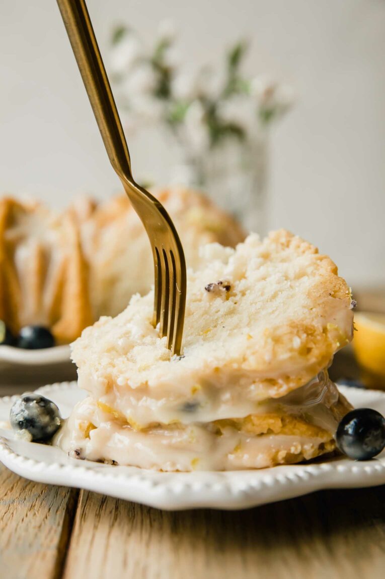 Fork taking bite out of slice of Vegan Lemon Blueberry Cake.