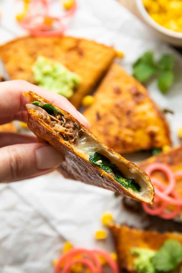 Hand holding side angle of Birria Quesadilla.