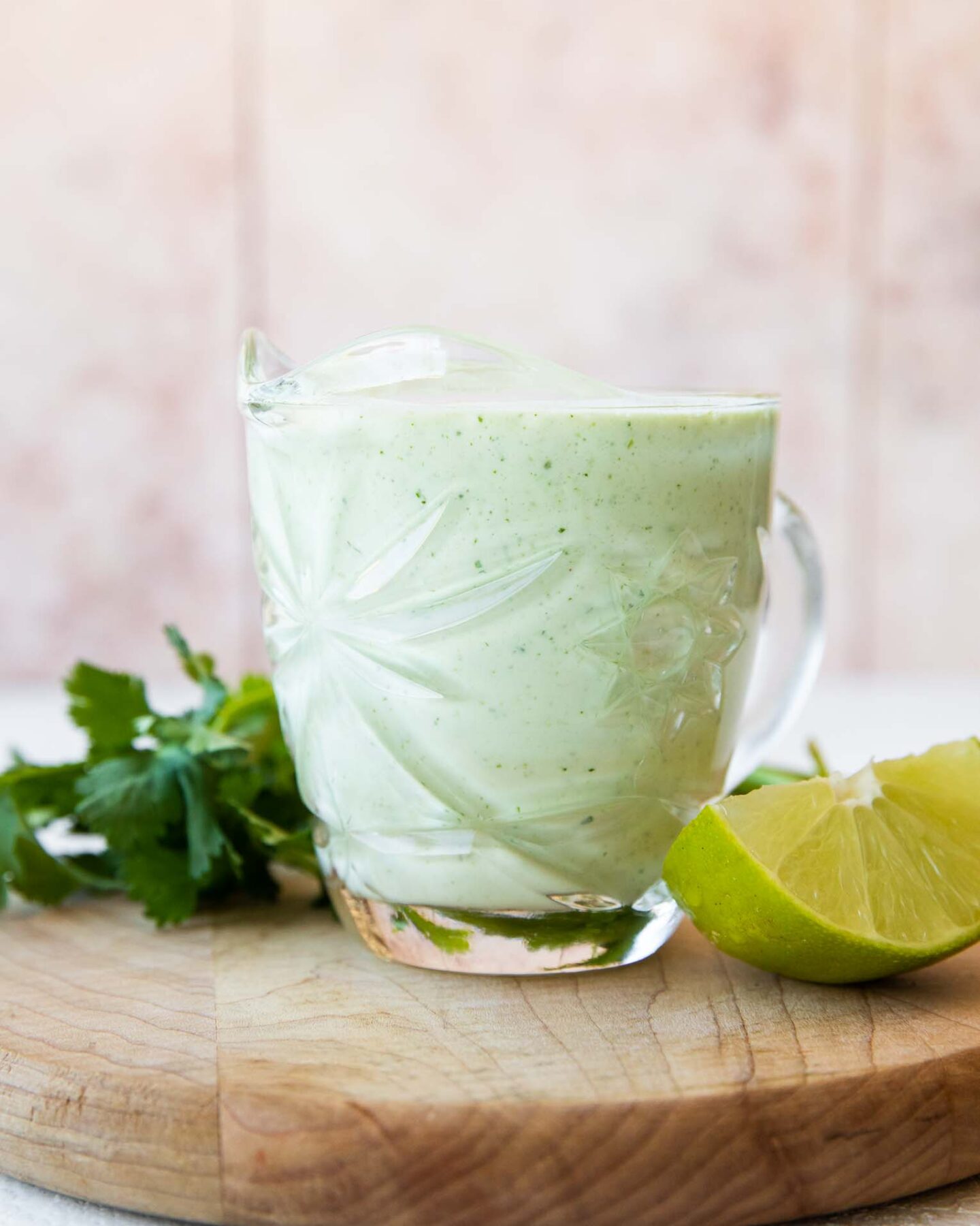 Cilantro Lime Sauce in a glass with cilantro and lime.
