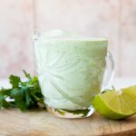 Cilantro Lime Sauce in a glass with cilantro and lime.