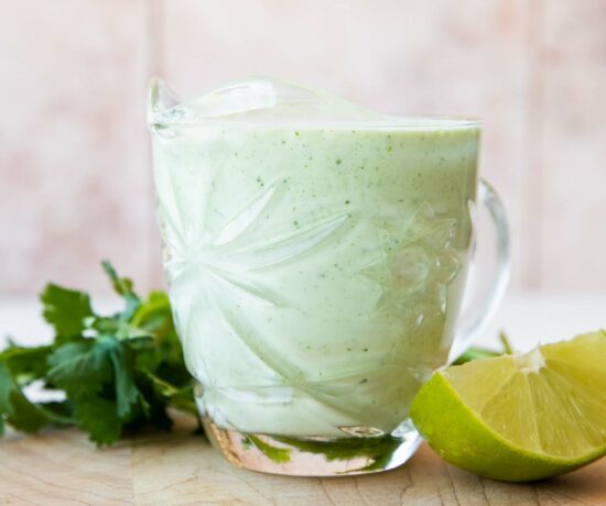 Cilantro Lime Sauce in a glass with cilantro and lime.