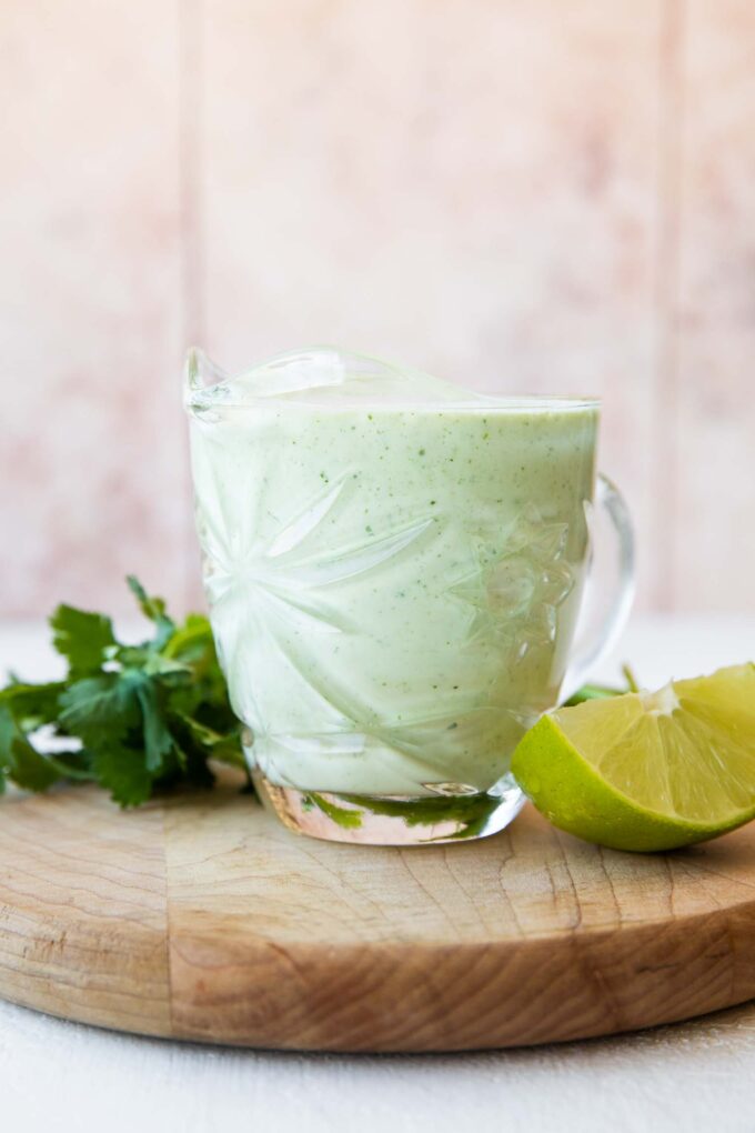 Cilantro Lime Sauce in a glass with cilantro and lime.
