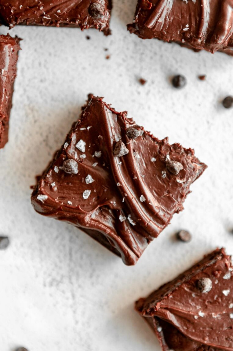 Close up of tahini brownie with icing and chocolate chips.