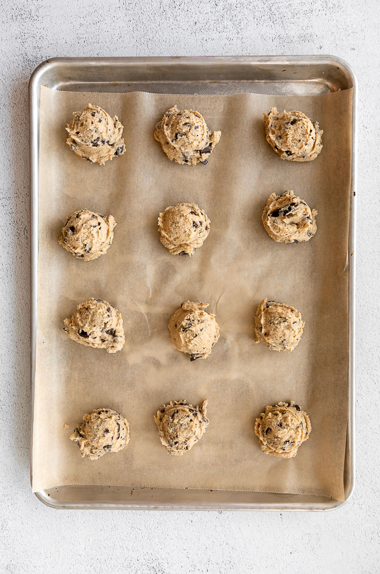 Tahini chocolate chip cookie dough balls on a baking sheet.